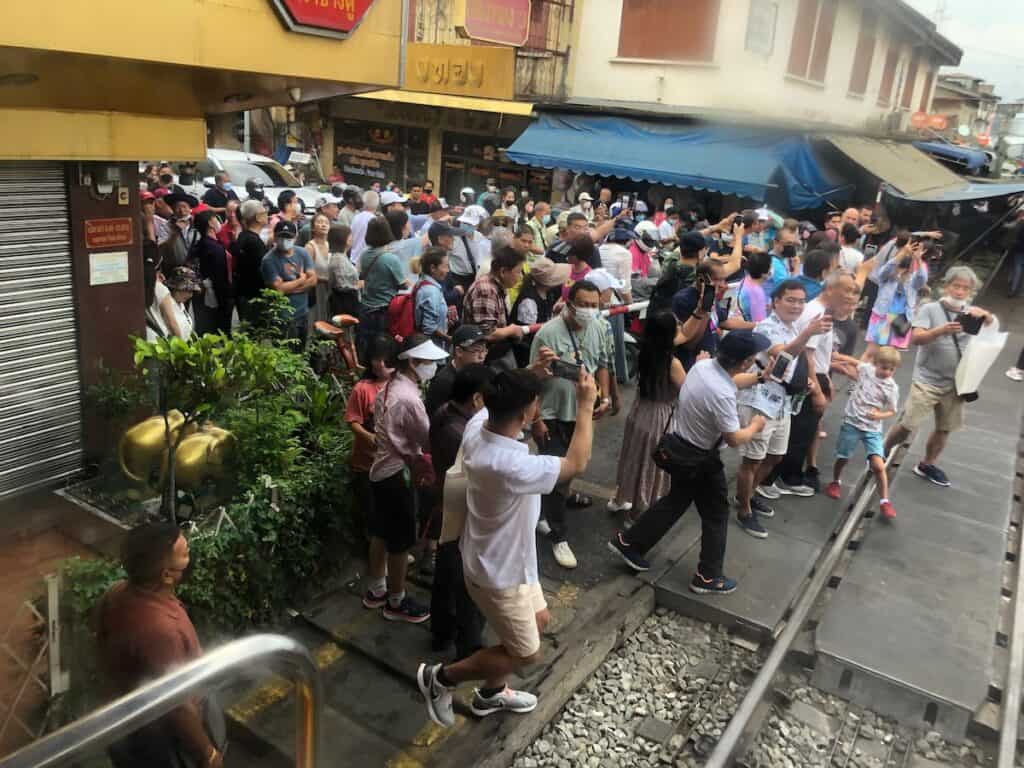 People waiting for the train to go by so they can cross the street at the maeklong railway market