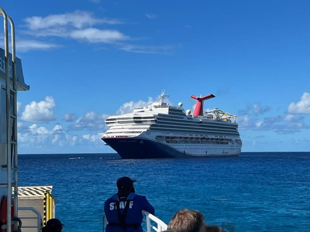Carnival Cruise ship with security staff looking on from the deck of a tender