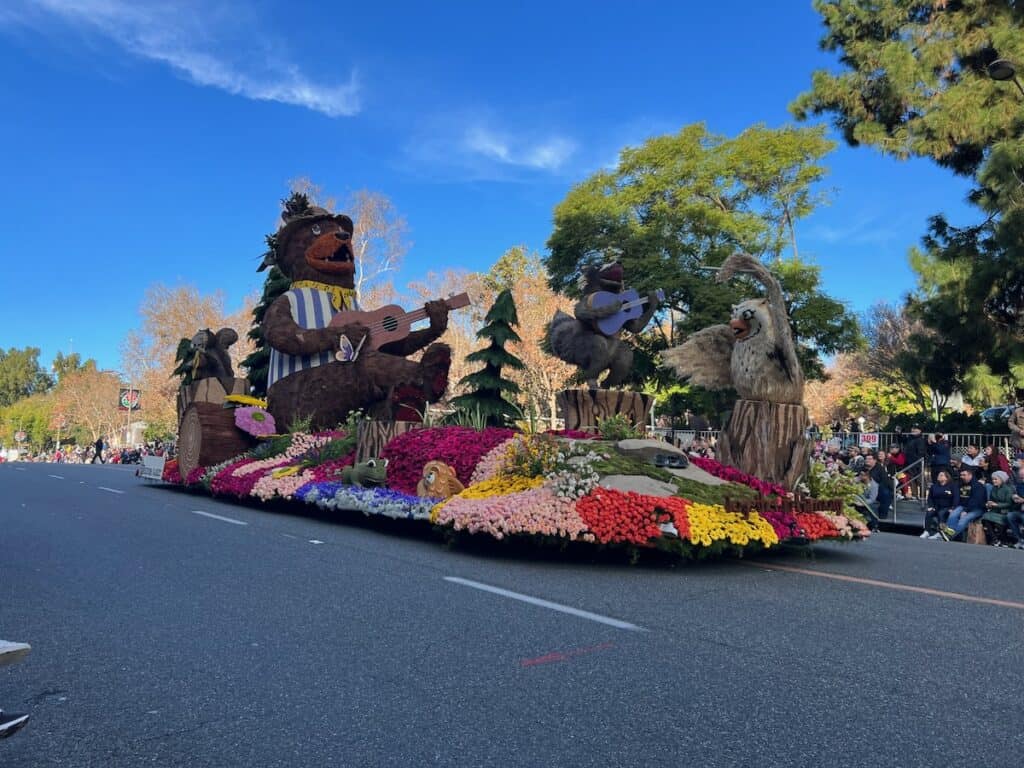 Colorful float at rose parade with a bear, owl and other animals