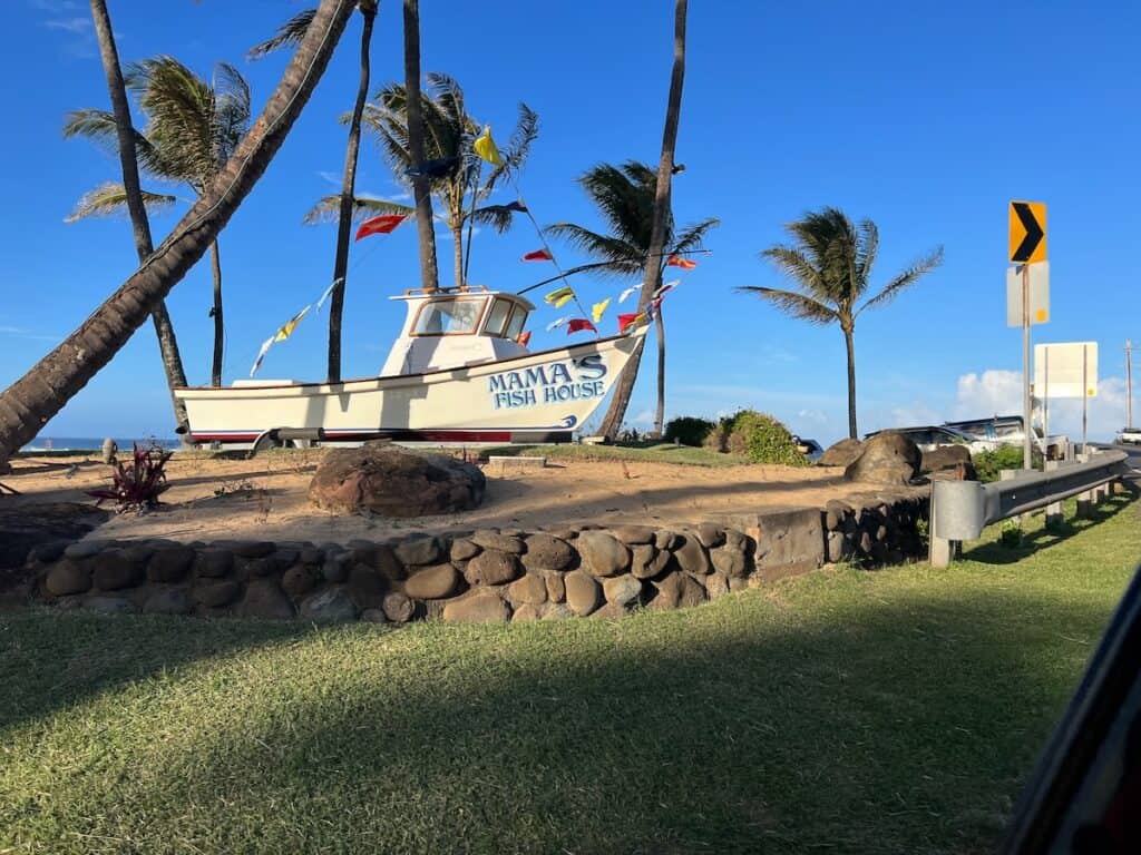 The sign to Mama's Fish House located on the road is a boat with the name on the side