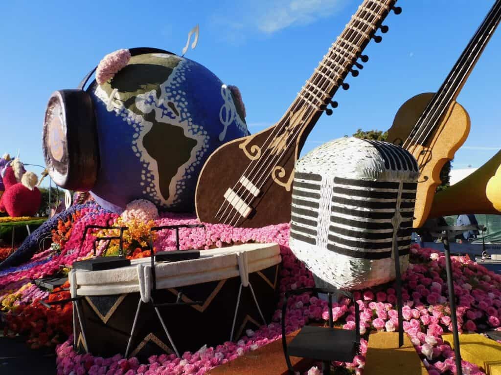 Giant microphone and musical instruments with a globe with headphones on a rose parade float