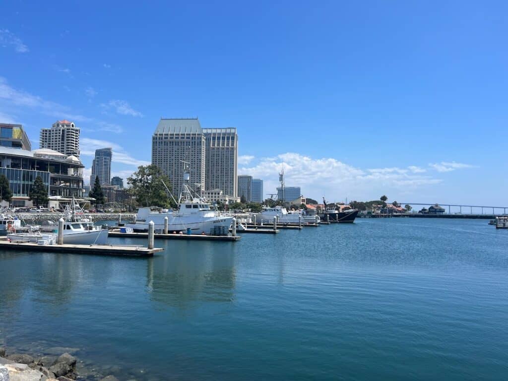 San Diego Harbor skyline view from the water with boats docked and Hyatt and Coronado Bridge in the background