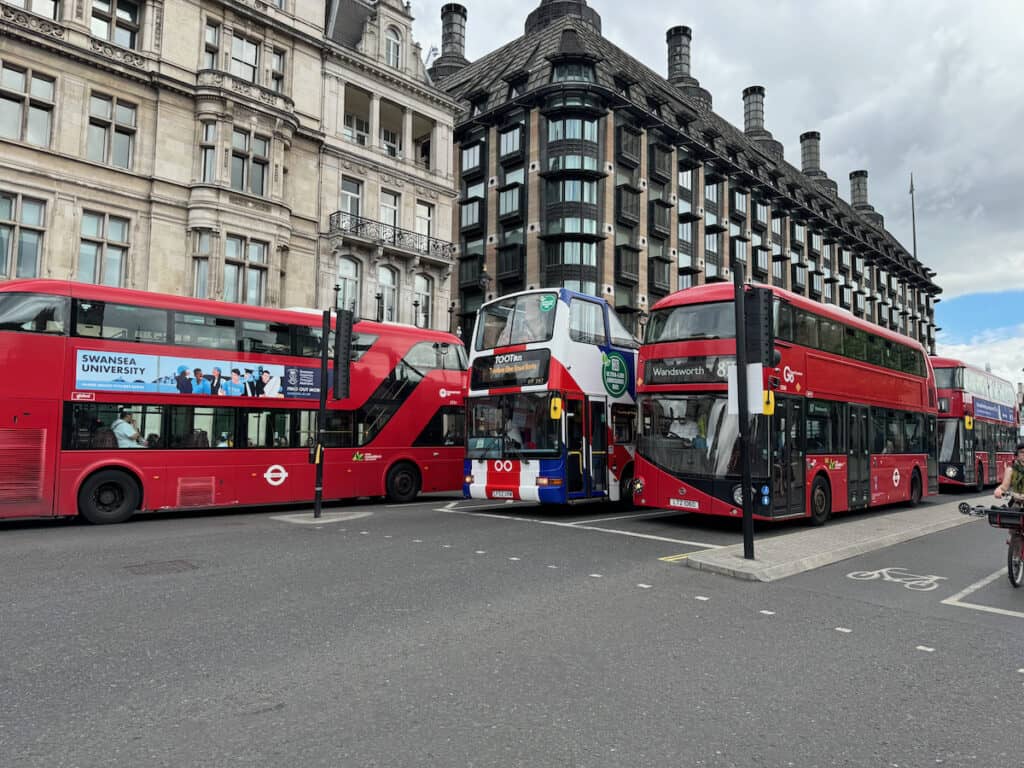 3 red double decker london public city buses with a tootbus in London