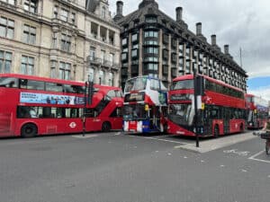 3 red double decker london public city buses with a tootbus in London