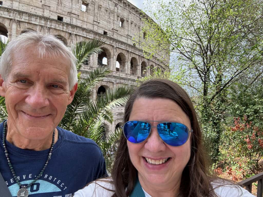 My husband and I with the colosseum and trees in the background
