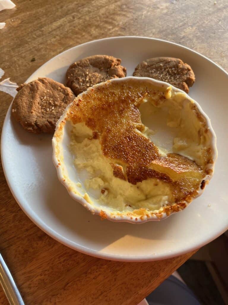 A plate with a half eaten coconut cream brulee and cookies.