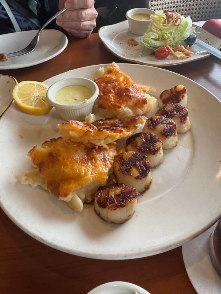 Seared Scallaops with 2 sides of AuGratin Potatos, with 1/2 a wedge salad in the backgroud. Shared entree
