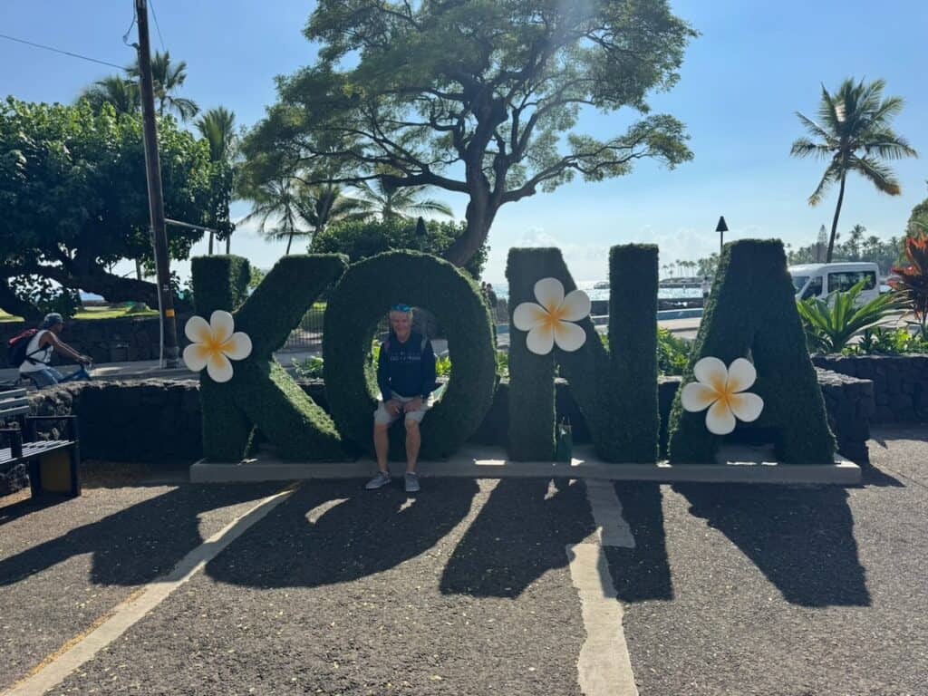 My husband sitting in the KONA sign