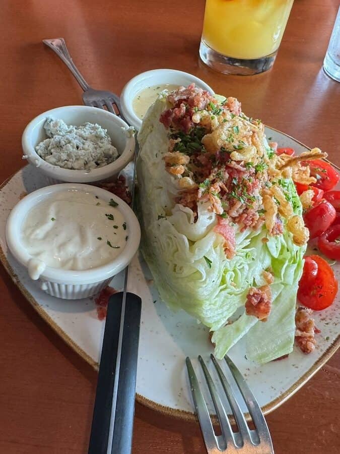 1/2 of wedge salad with blue cheese and dressing on the side
